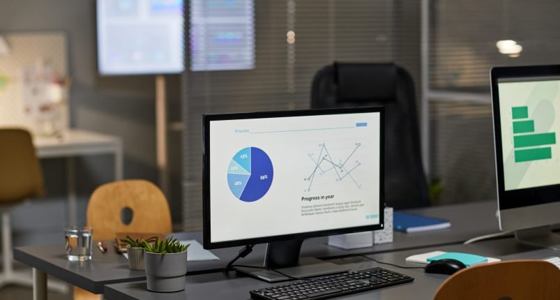 Background image of computer monitor in office with marketing charts, copy space